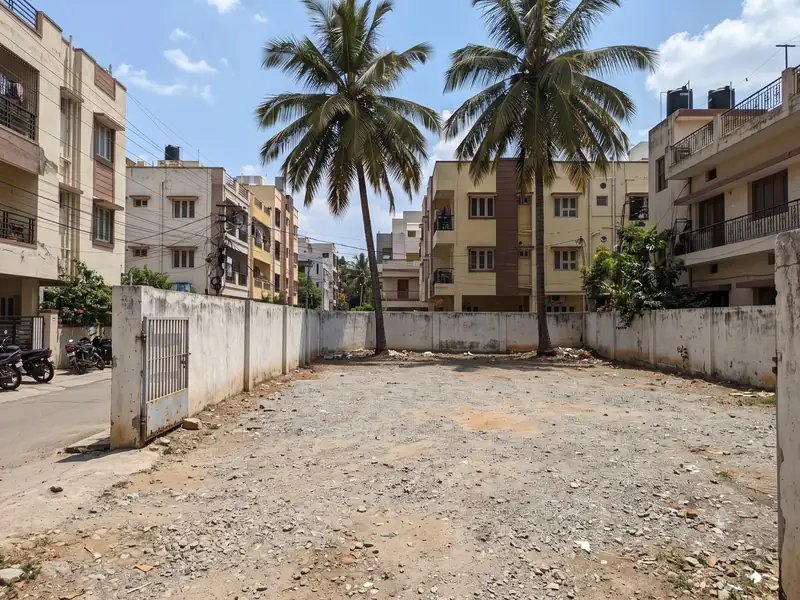 Walled open plot with a gravel surface and coconut trees