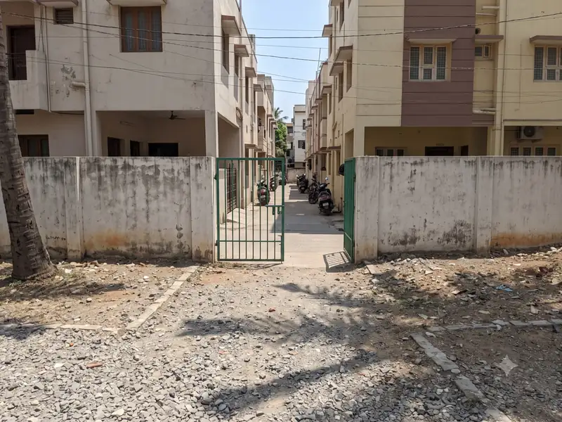 Open plot with a small side gate between two apartment buildings