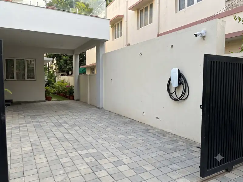 Covered car porch with a paved floor, wall-mounted EV charger and CCTV camera