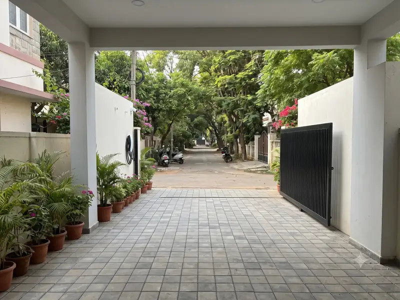 Gated driveway under a porch roof, lined with potted plants